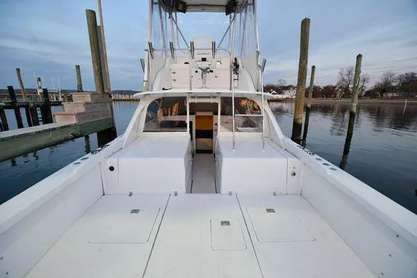 Slide: The Image of 1965 Bertram Sportfisher boat docked, showcasing spacious deck and fishing amenities. - 11