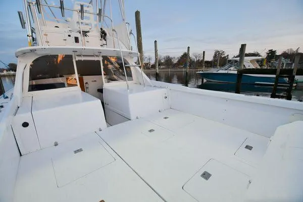 Slide: The Image of 1965 Bertram Sportfisher boat docked, showcasing spacious deck and fishing amenities. - 12