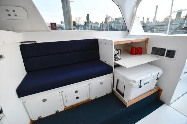Slide: The Image of 1965 Bertram Sportfisher interior with navy seating, storage, and cooler. - 18
