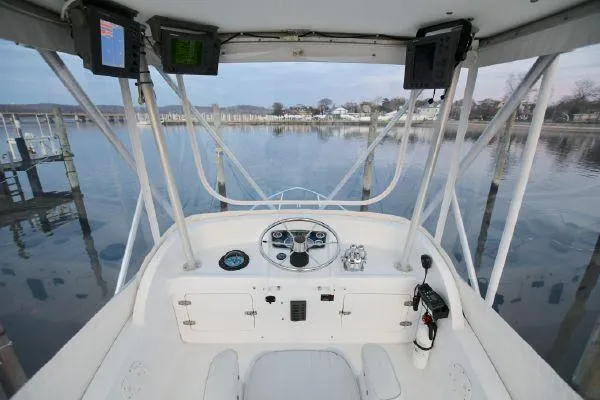 Slide: The Image of 1965 Bertram Sportfisher boat helm with steering wheel and navigation equipment, docked by calm waters. - 24