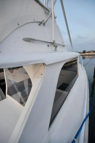 Slide: The Image of 1965 Bertram Sportfisher boat, white exterior, docked by calm water. - 27