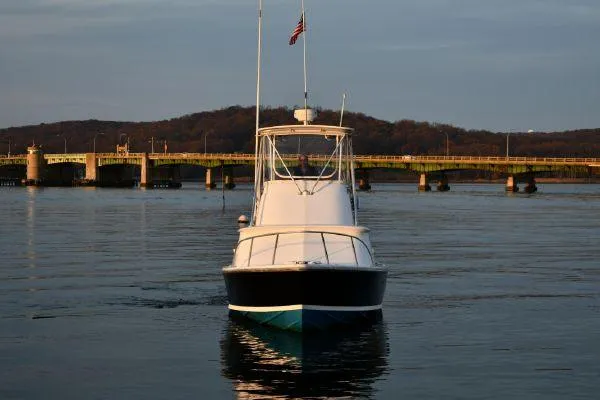 Slide: The Image of 1965 Bertram Sportfisher boat on calm water near a bridge at sunset. - 7