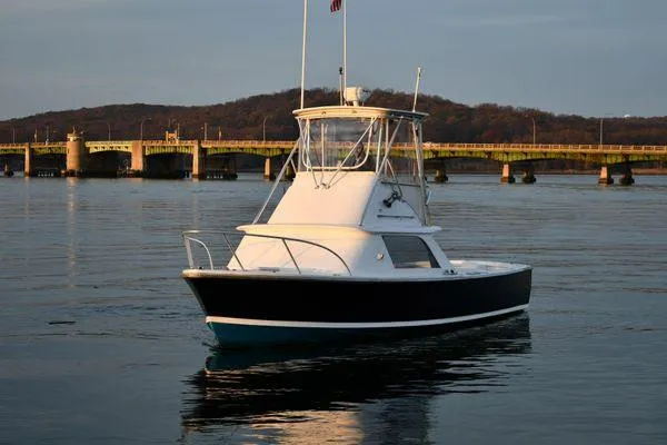 Slide: The Image of 1965 Bertram Sportfisher boat on calm water near a bridge at sunset. - 8