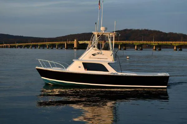 Slide: The Image of 1965 Bertram Sportfisher boat on calm water near a bridge at sunset. - 9