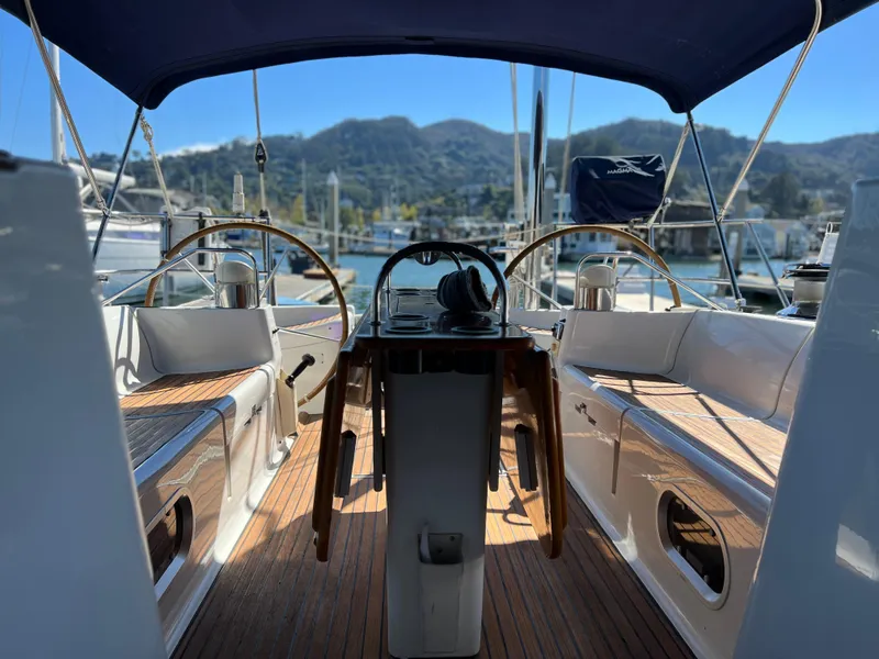 Slide: The Image of Cockpit view of 2000 Jeanneau 52.2 sailboat with dual steering wheels and scenic marina backdrop. - 37