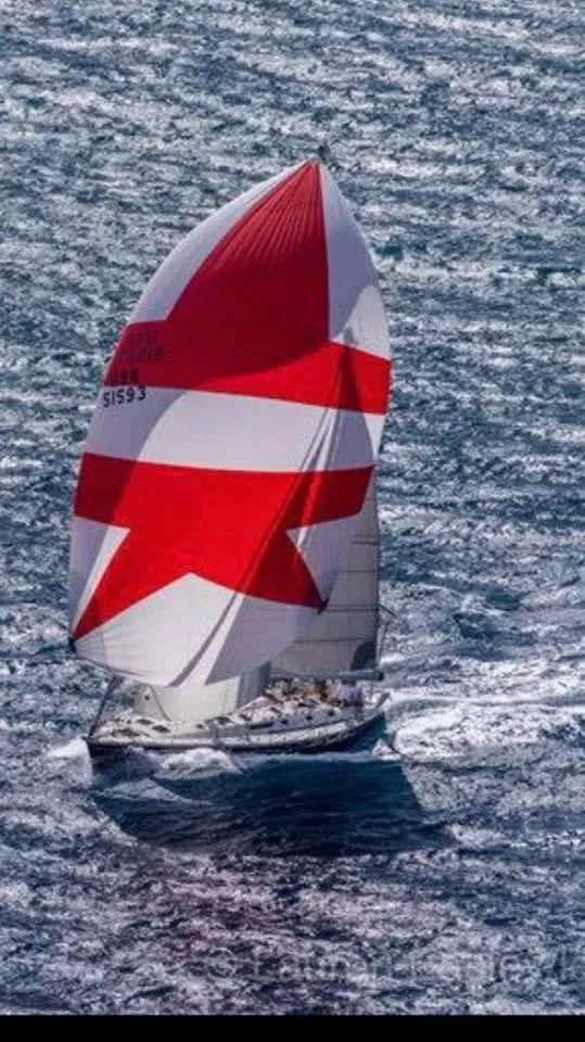Slide: The Image of Sailing yacht Jeanneau 52.2 (2000) with red and white spinnaker on open water. - 4