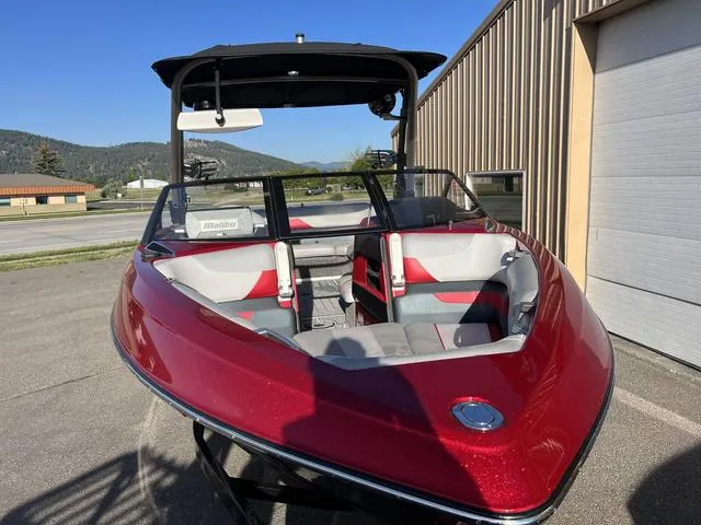 Slide: The Image of 2017 Malibu 23 LSV boat, red exterior, parked outdoors near a building. - 3