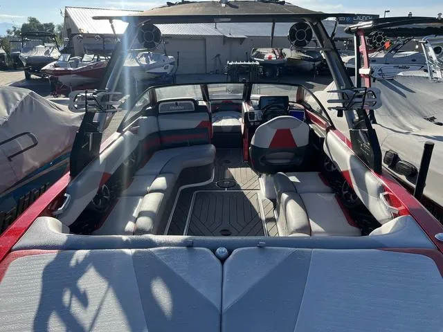 Slide: The Image of 2017 Malibu 23 LSV boat interior with seating and speakers, docked outdoors. - 5