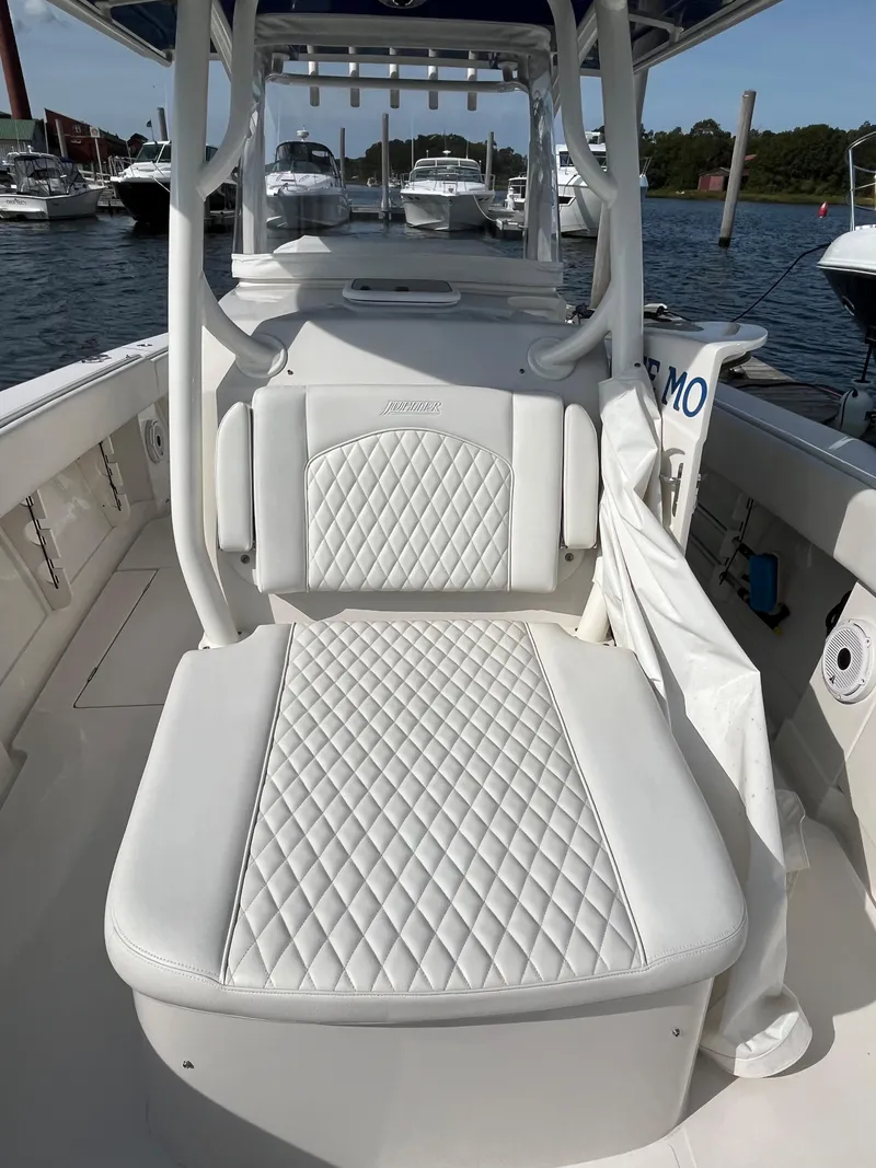 Slide: The Image of 2020 Jupiter 34 Center Console boat with white quilted seating, docked in a marina. - 12