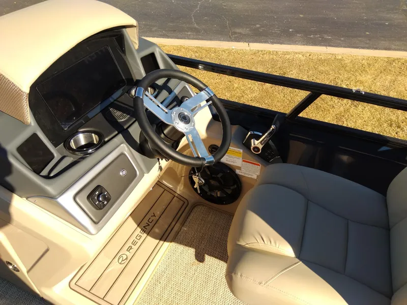 Slide: The Image of 2024 Regency 250 LE3 boat cockpit with steering wheel and beige seating. - 13