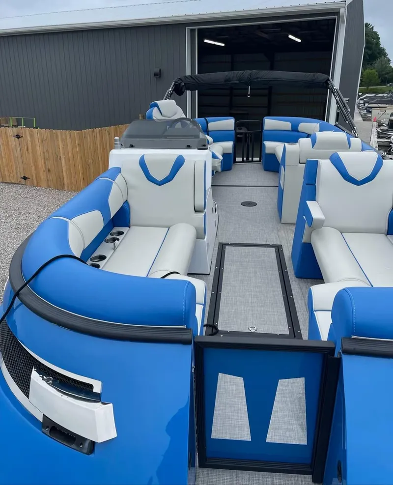 Slide: The Image of 2021 Montara 23' Surfboss boat with blue and white seating, docked near a building. - 4