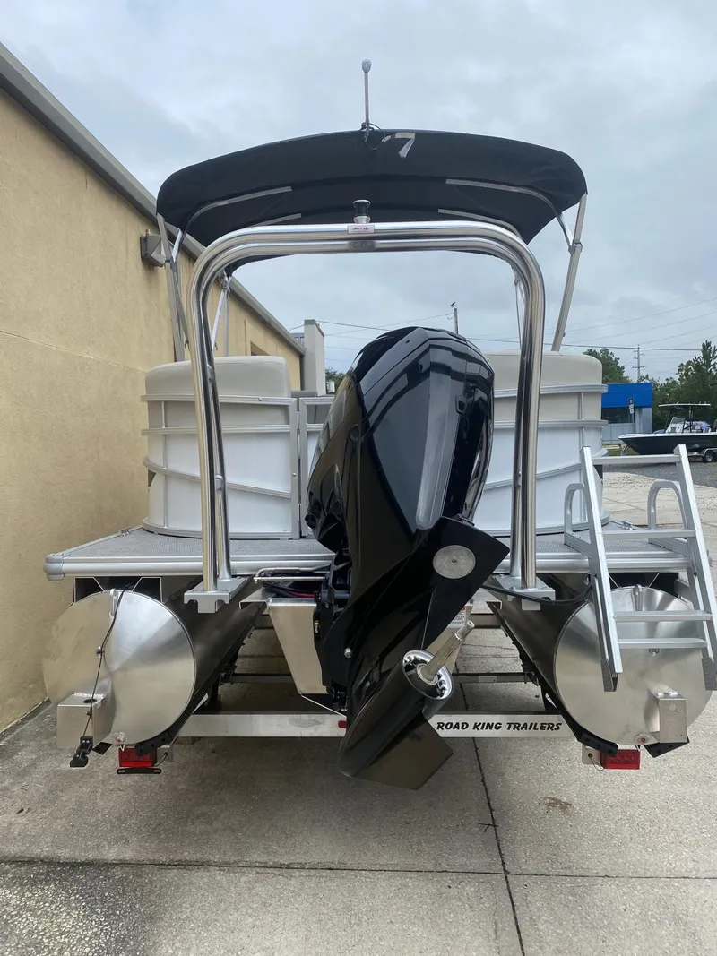Slide: The Image of 2024 Starcraft LX 20 R pontoon boat with outboard motor, parked outdoors. - 4