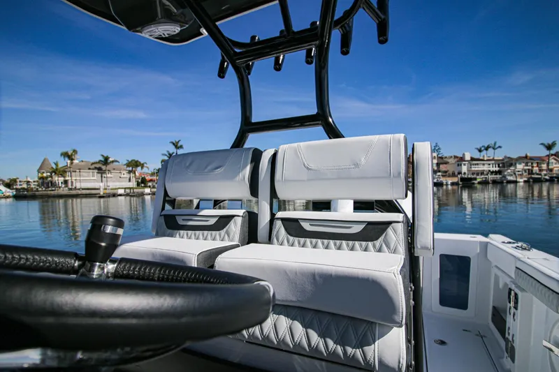 Slide: The Image of 2023 Blackfin 302 CC boat interior with dual seats and steering wheel, dockside view. - 12