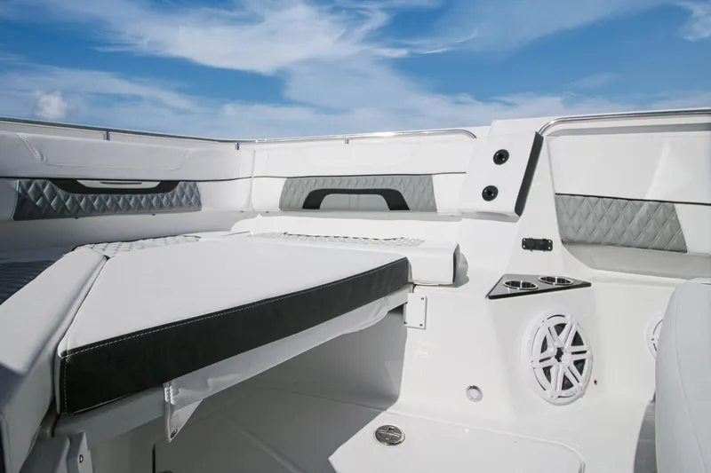 Slide: The Image of 2023 Blackfin 302 CC boat interior with cushioned seating and speaker, under a clear blue sky. - 8