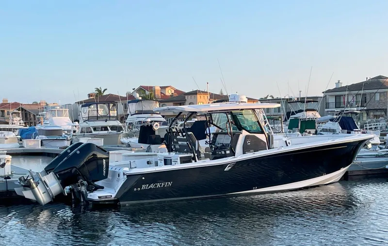 The Image of 2024 Blackfin 332 CC boat docked in marina, surrounded by other vessels. - 0