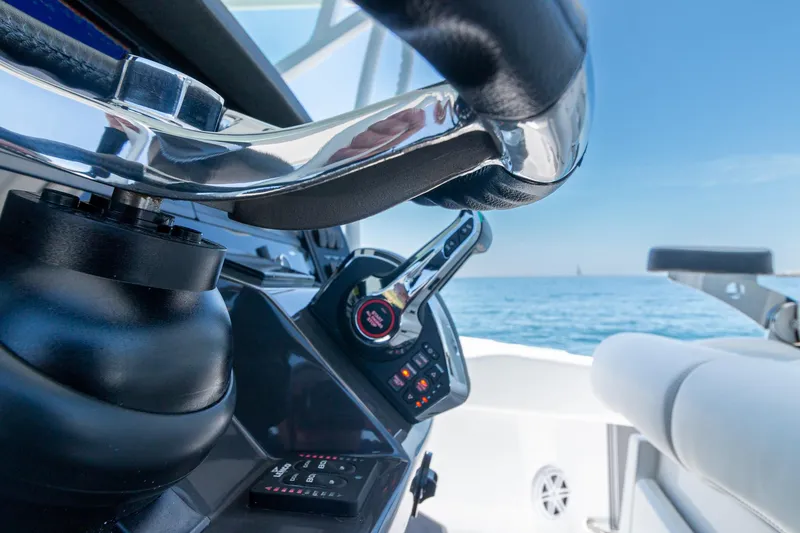 Slide: The Image of 2024 Blackfin 332 CC boat helm with ocean view, featuring steering wheel and controls. - 10