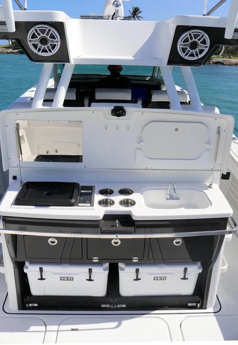 Slide: The Image of 2025 Blackfin 400 CC boat kitchen with sink, stove, and storage, set against a blue ocean backdrop. - 14