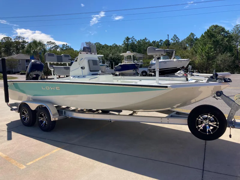 Slide: The Image of 2022 Lowe BAY 20 boat on a trailer in a parking lot. - 1