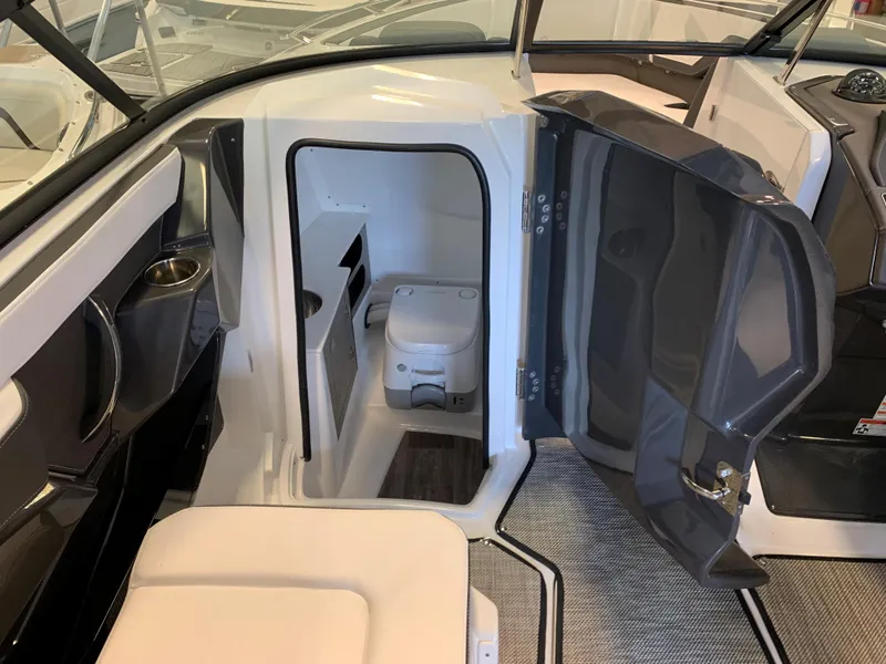 Slide: The Image of 2024 Monterey 258 Super Sport boat interior with open door to compact bathroom. - 8