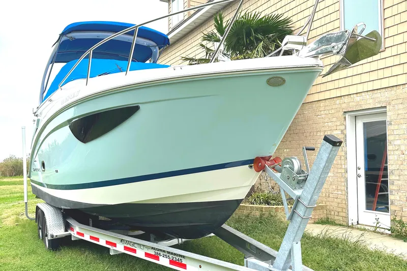 Slide: The Image of 2022 Regal 26XO boat on a trailer near a brick house. - 13