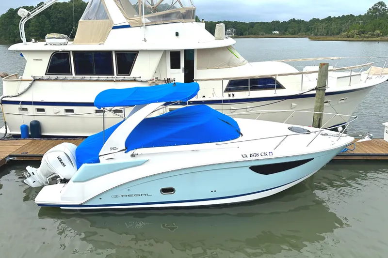 Slide: The Image of 2022 Regal 26XO boat docked with blue cover, side view. - 18