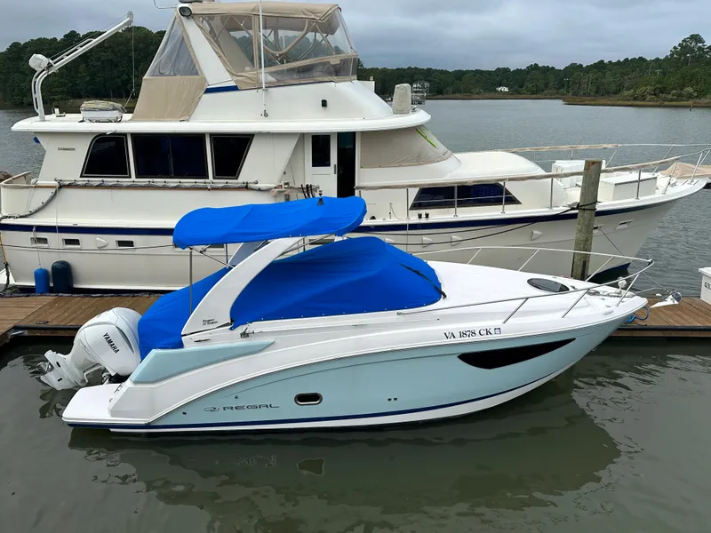 Slide: The Image of 2022 Regal 26XO boat docked with blue cover and canopy. - 2
