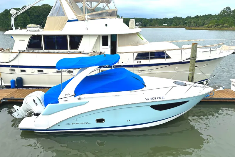 Slide: The Image of 2022 Regal 26XO boat docked beside a larger yacht on a calm waterway. - 20