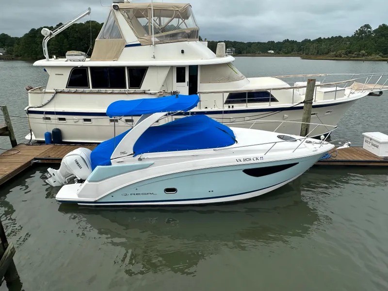 Slide: The Image of 2022 Regal 26XO boat docked beside a larger yacht on a cloudy day. - 3