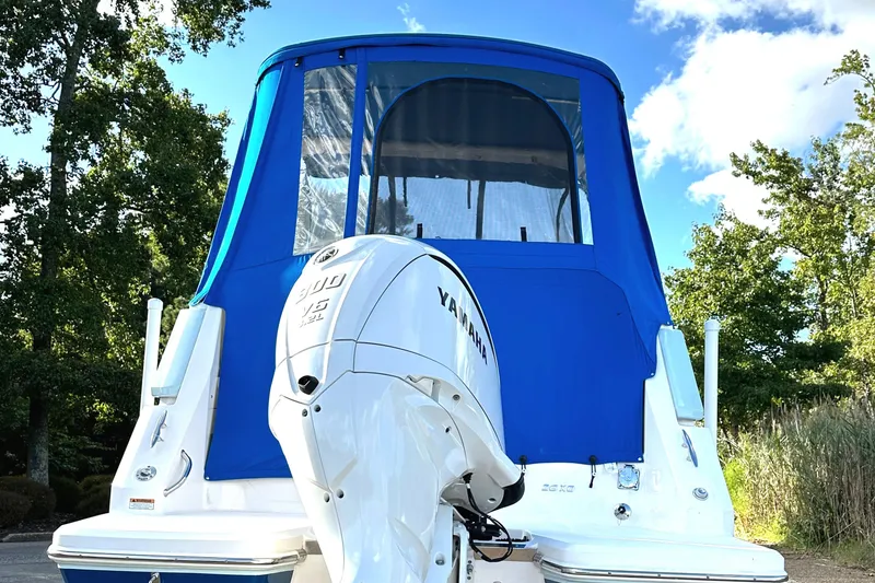 Slide: The Image of 2022 Regal 26XO boat with Yamaha outboard motor and blue canopy, surrounded by trees. - 47
