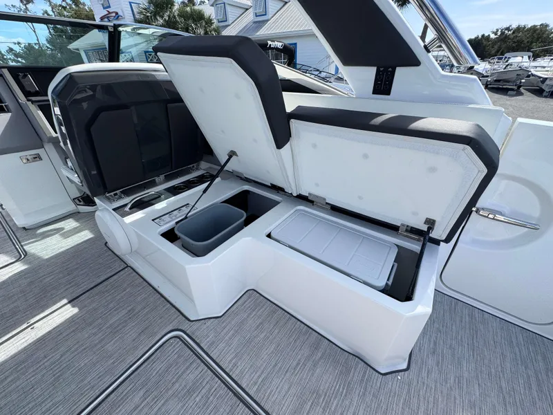 Slide: The Image of Open storage compartments on a 2024 Cobalt R33 boat with integrated cooler and trash bin. - 22