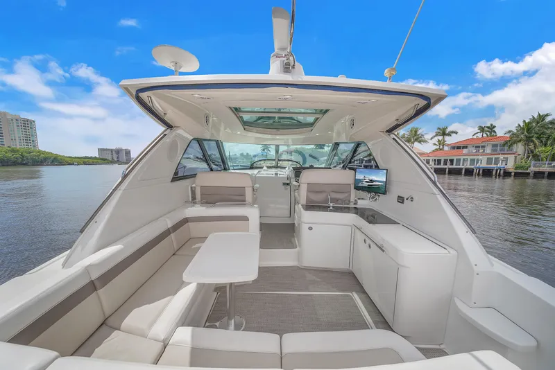 Slide: The Image of 2013 Sea Ray 450 Sundancer yacht interior with seating, table, and kitchenette under a clear blue sky. - 16