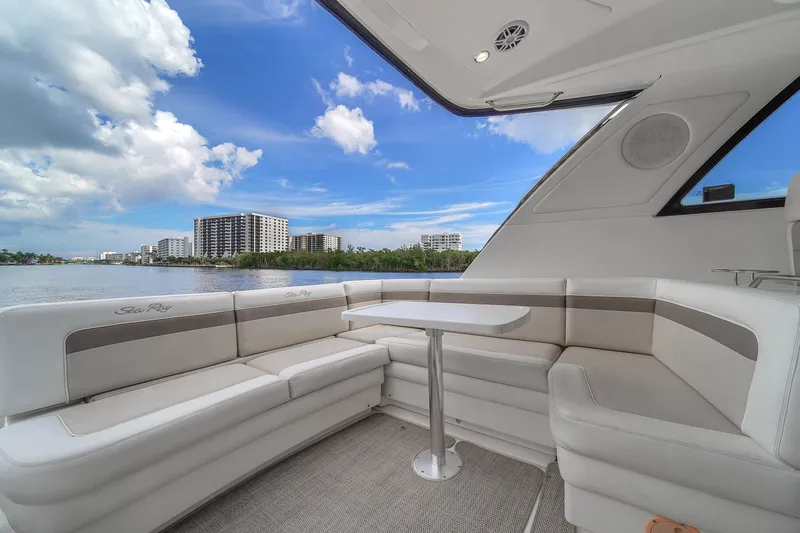 Slide: The Image of 2013 Sea Ray 450 Sundancer yacht interior with seating and table, overlooking waterfront cityscape. - 18