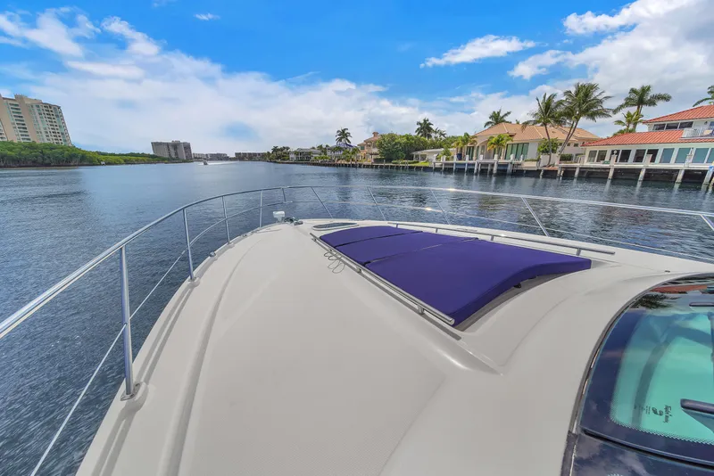 Slide: The Image of 2013 Sea Ray 450 Sundancer yacht cruising on a scenic waterfront with palm trees and buildings. - 44