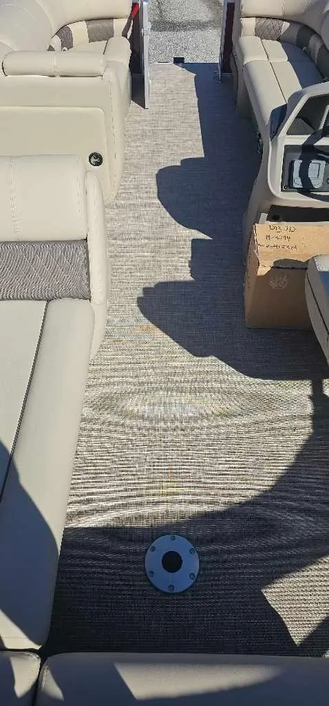 Slide: The Image of 2024 Sun Tracker Party Barge 20 DLX interior with beige seating and carpeted floor. - 3