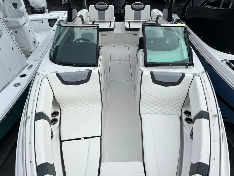 Slide: The Image of 2023 Chaparral 250 OSX boat with white and gray interior, dual windshields, and spacious seating. - 14
