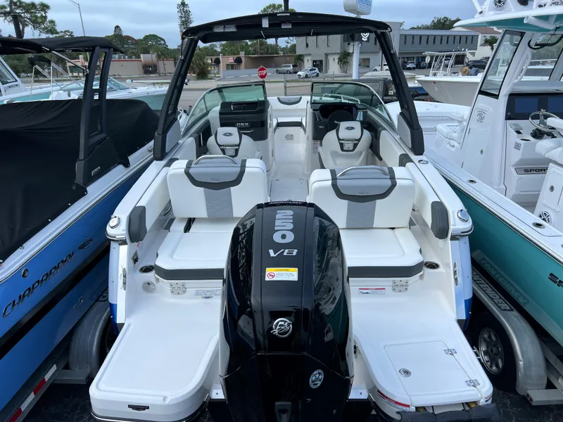 Slide: The Image of 2023 Chaparral 250 OSX boat with V8 engine, white and gray seating, docked among other boats. - 5