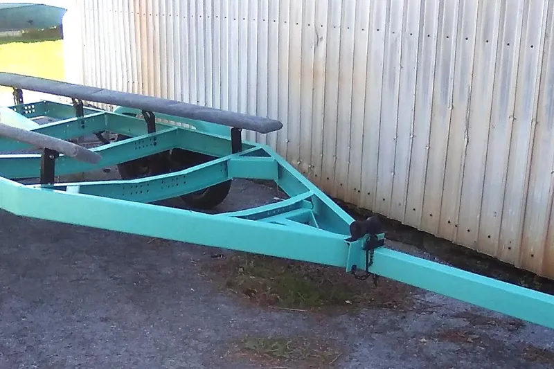 Slide: The Image of Turquoise boat trailer for 1963 Coronado 21 by Century, parked on gravel near a corrugated wall. - 15