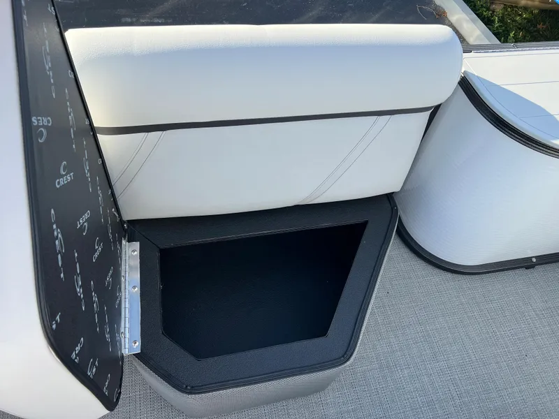Slide: The Image of 2024 Crest Classic LX 220 boat interior storage compartment with white cushioned seating. - 10