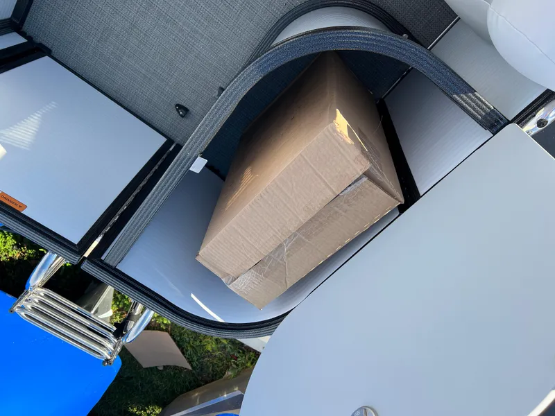 Slide: The Image of Storage compartment of 2024 Crest Classic LX 220 pontoon boat with a cardboard box inside. - 11