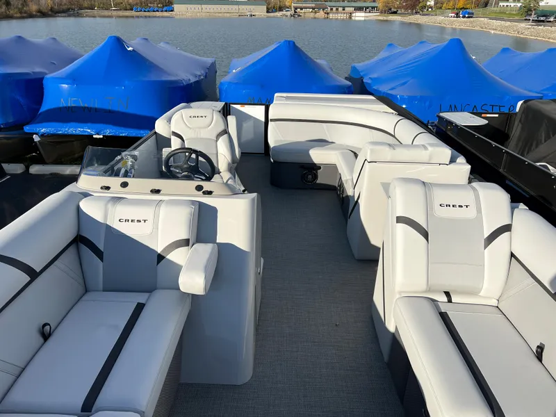 Slide: The Image of 2024 Crest Classic LX 220 pontoon boat with spacious seating on a lake. - 5