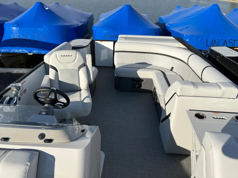 Slide: The Image of 2024 Crest Classic LX 220 pontoon boat interior with plush seating and steering console. - 8