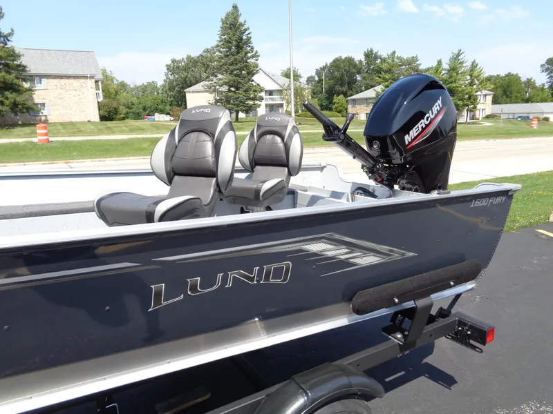 Slide: The Image of 2024 Lund 1600 Fury Tiller boat with Mercury engine, parked outdoors. - 2