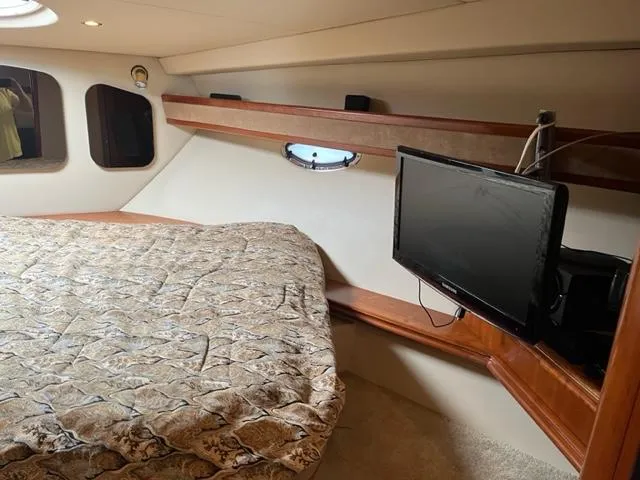 Slide: The Image of 2003 Cruisers Yachts 3772 Express cabin with bed, TV, and porthole windows. - 14