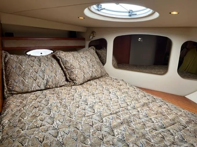 Slide: The Image of 2003 Cruisers Yachts 3772 Express cabin with patterned bedding and porthole window. - 15