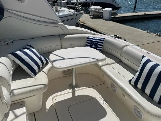 Slide: The Image of 2003 Cruisers Yachts 3772 Express interior with striped cushions and table, docked by the water. - 17