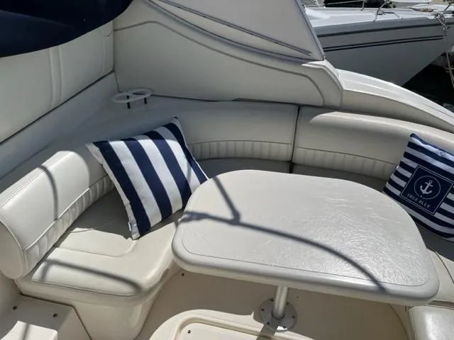 Slide: The Image of 2003 Cruisers Yachts 3772 Express interior seating area with striped cushions and table. - 19