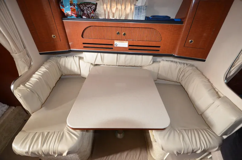 Slide: The Image of 2003 Sea Ray 280 DA cabin dinette with cushioned seating and wooden cabinetry. - 14