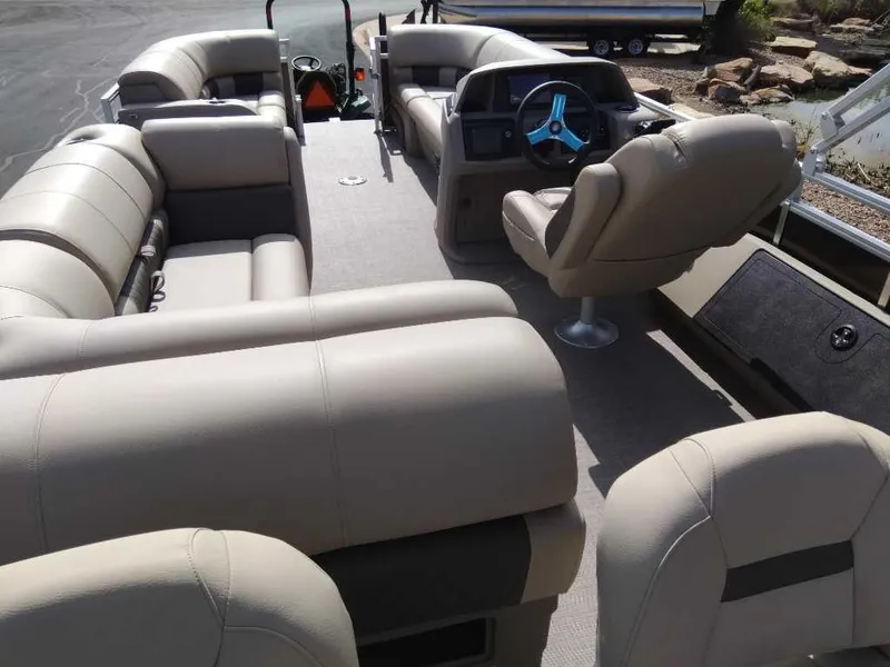 Slide: The Image of 2024 Sun Tracker SportFish 22 DLX pontoon boat interior with beige seating and captain's chair. - 5