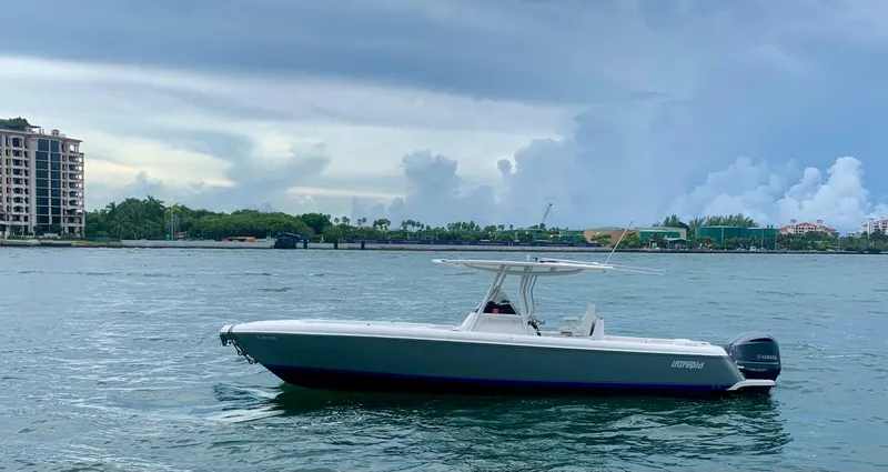 The Image of 2012 Intrepid 327 Center Console boat on calm waters with a cityscape background. - 0