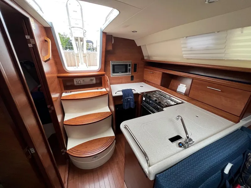 Slide: The Image of 2014 Marlow-Hunter e33 yacht interior with kitchen, stairs, and wooden cabinetry. - 10